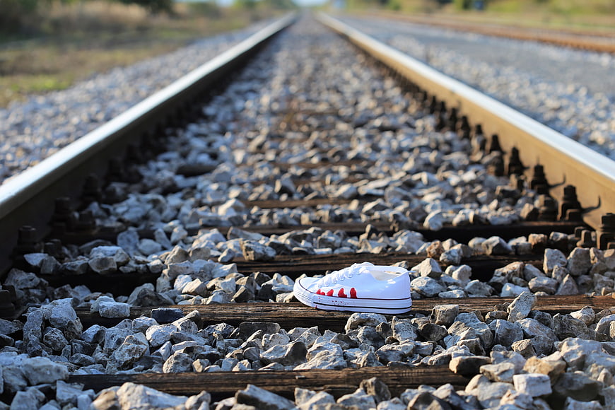 Bloody white sneaker on railway tracks symbolizing teen suicide