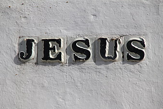 Ceramic tiles spelling Jesus on a white textured wall