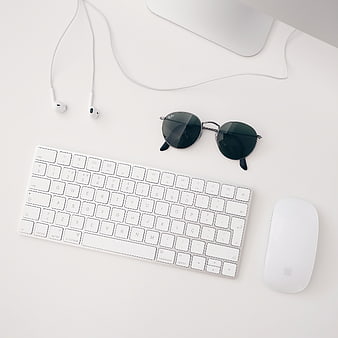 Minimalist white workspace with keyboard, mouse, sunglasses, and earphones