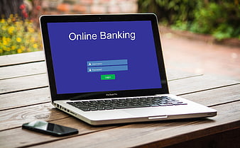 Laptop displaying online banking login screen on wooden table