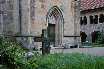 Modern stone cross in front of historic Gothic church courtyard