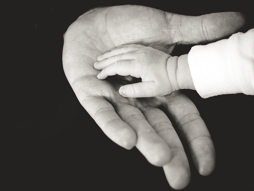 Black and white photo of baby hand in adult palm