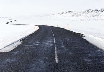 Winding asphalt road through snowy winter landscape