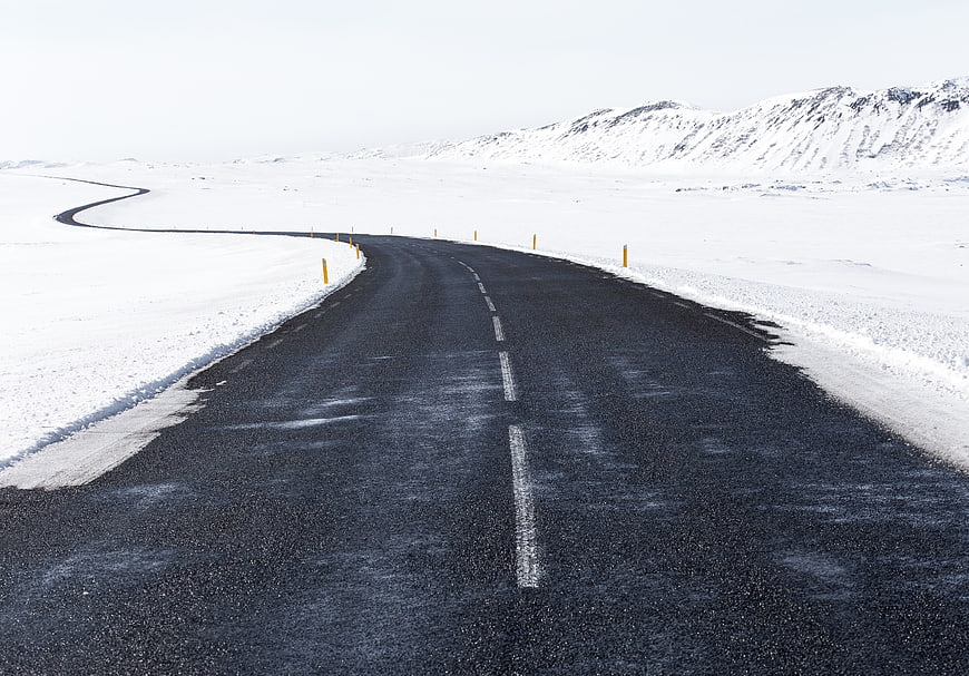 Winding asphalt road through snowy winter landscape