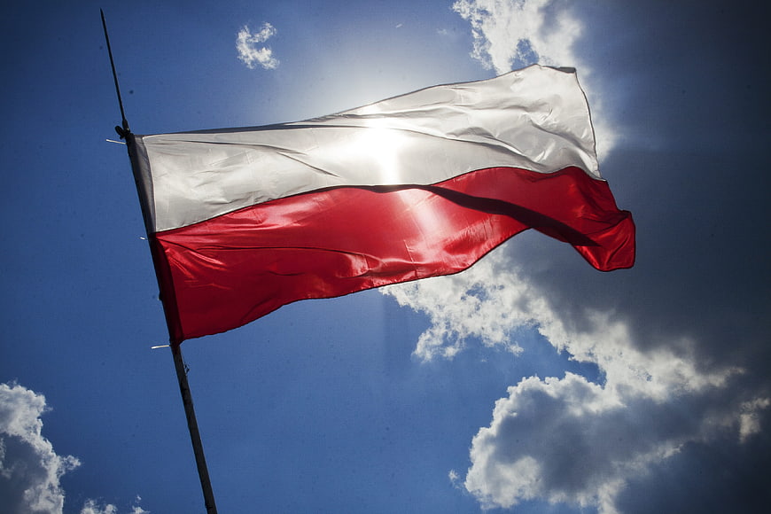 Polish flag waving against blue sky with clouds