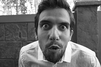 Close-up portrait of surprised young man in black and white