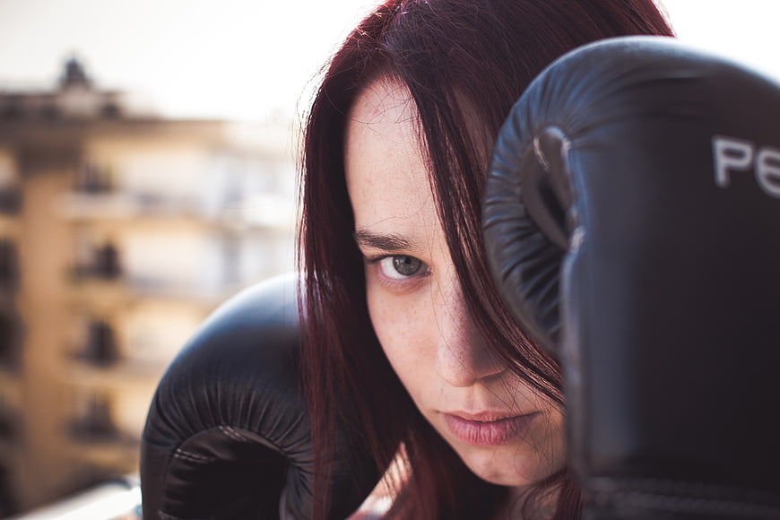 Intense female boxer with gloves on urban rooftop