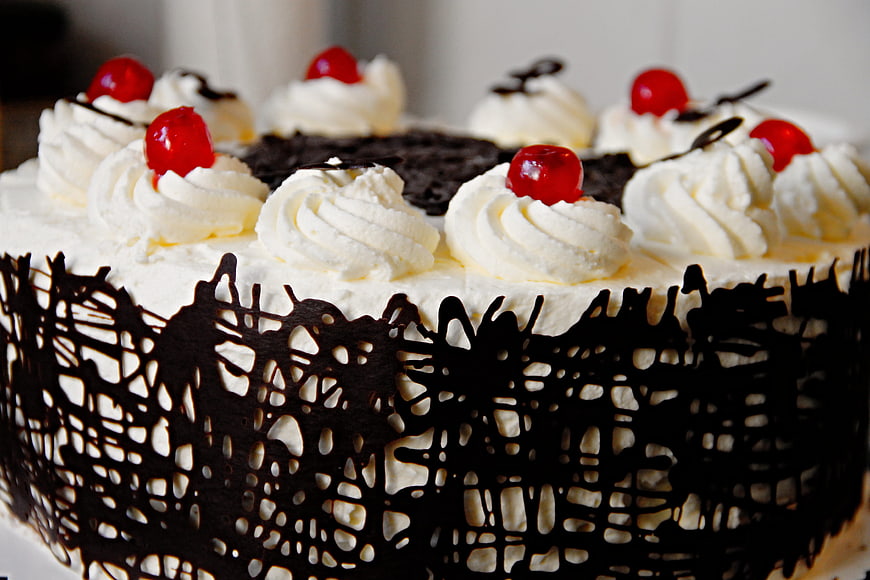 Chocolate cake with whipped cream, cherries, and chocolate lattice
