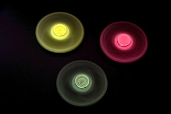 Three glowing LED fidget spinners on black background