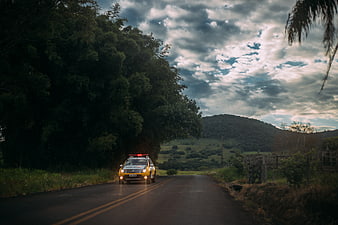 Police SUV driving on rural road with dramatic sky
