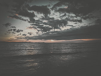Moody Sunset Over Dark Ocean with Cloudy Sky
