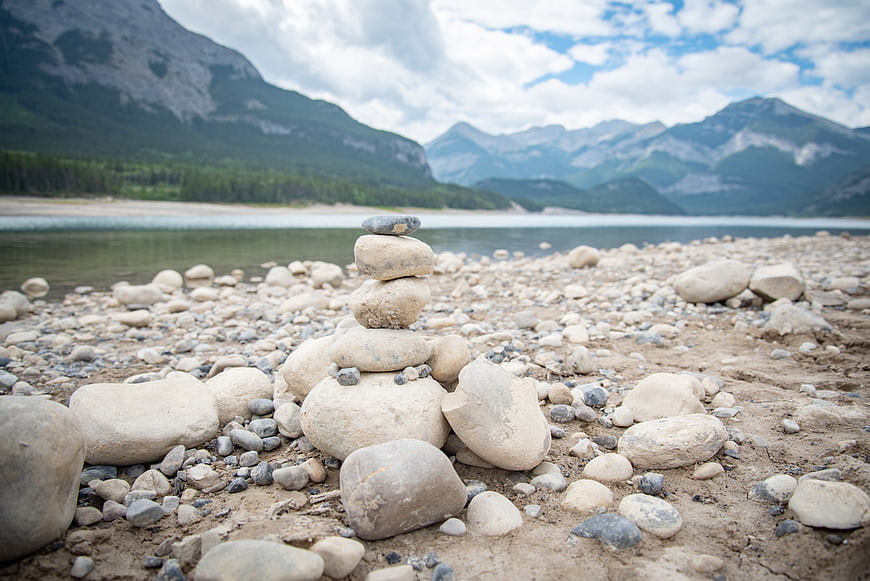 Stacked stones on rocky lake shore with mountains
