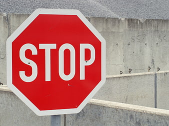 Red Stop Sign Against Gray Concrete Wall