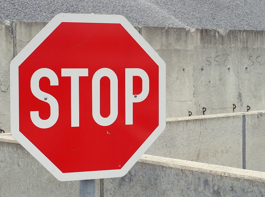 Red Stop Sign Against Gray Concrete Wall