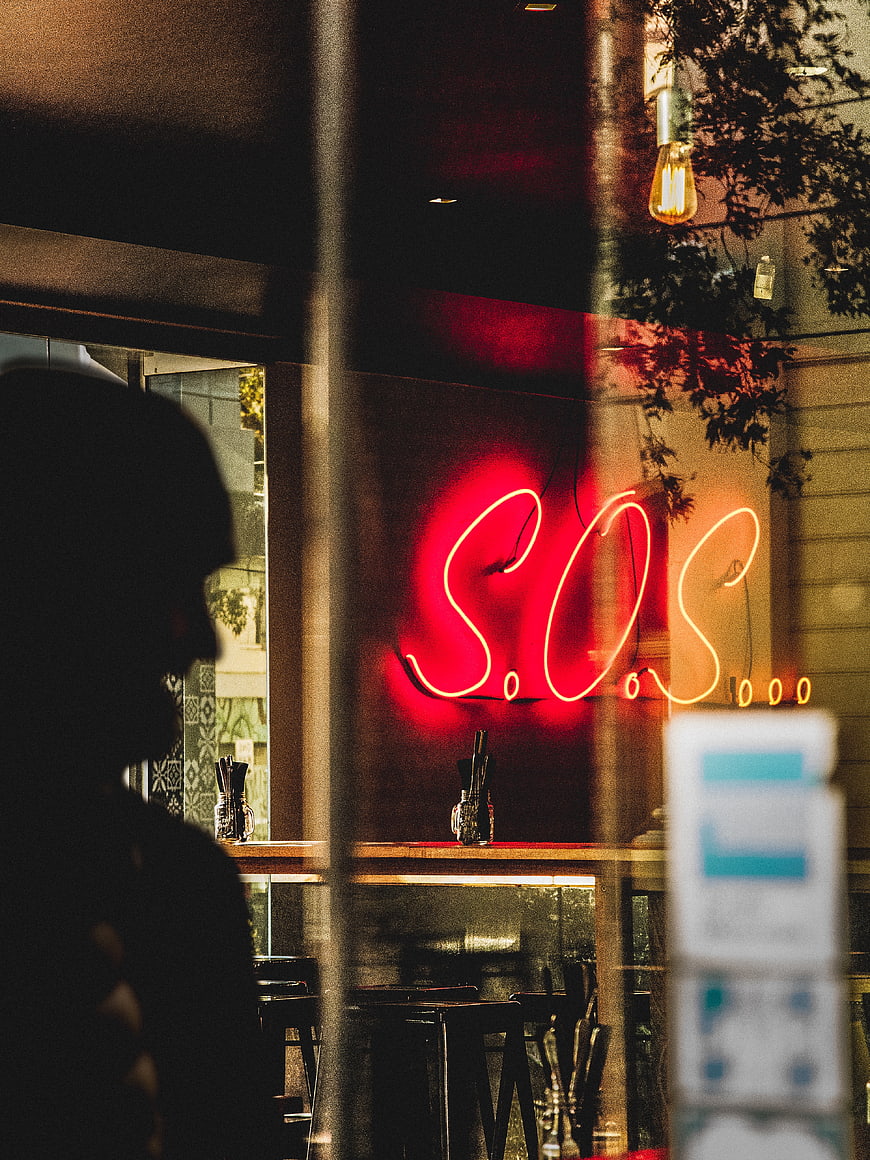 Red Neon S.O.S Sign in Restaurant Window at Night