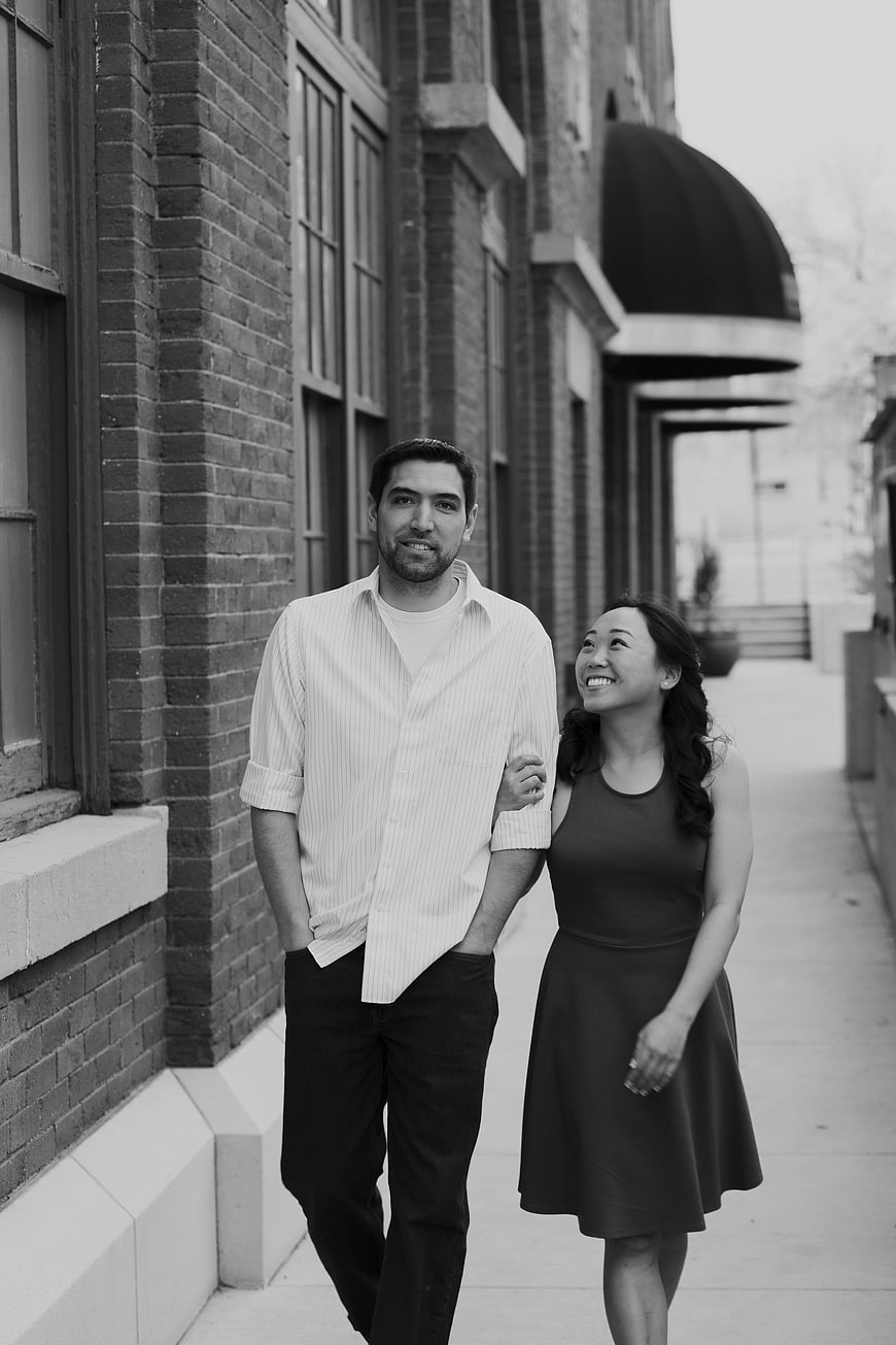 Happy engaged couple walking arm in arm on city sidewalk