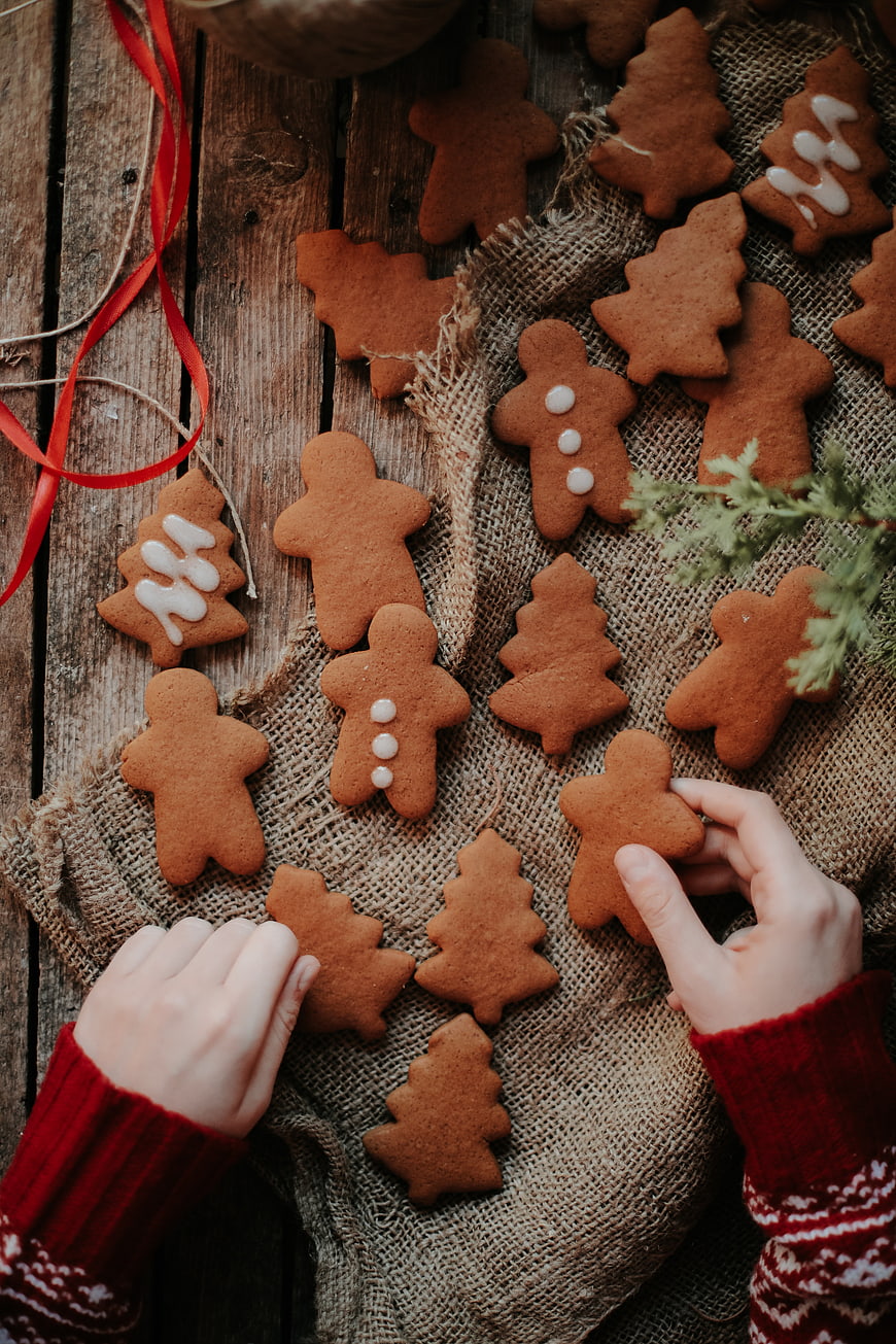 Hands Decorating Christmas Gingerbread Cookies on Wood