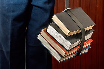 Stack of Books Held by Strap Against Blue Fabric