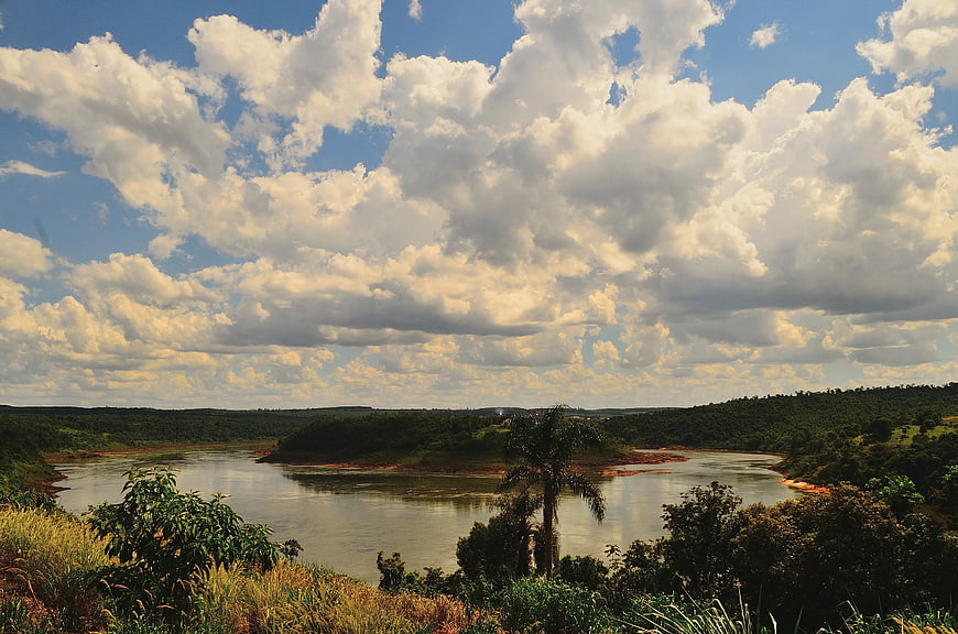 Wide River Landscape with Dramatic Clouds and Lush Green Hills