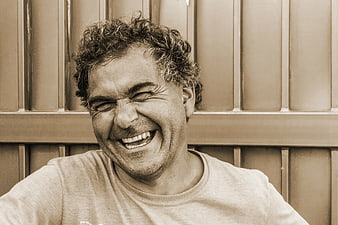 Laughing man with curly hair in sepia tone