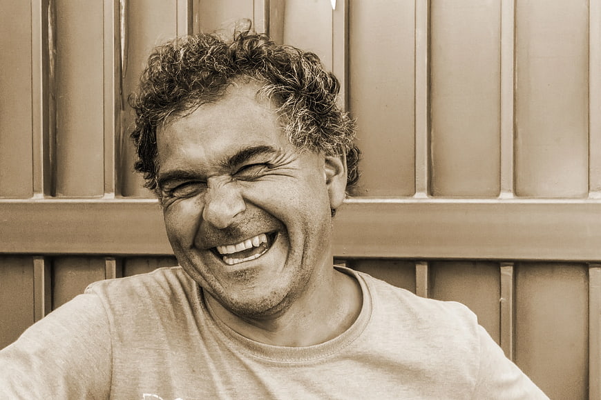 Laughing man with curly hair in sepia tone