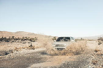 Vintage SUV Driving Through Dusty Desert Landscape