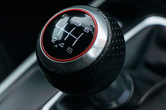 Close-up of a manual car gear shift knob with red accent ring
