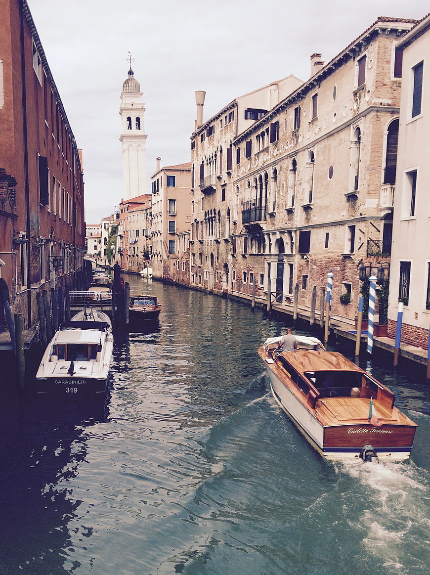 Classic wooden boat navigating a Venice canal with historic architecture