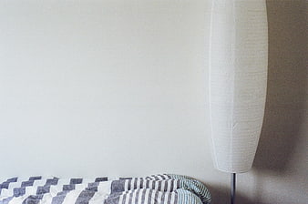 Minimalist Bedroom Corner with Striped Blanket and Floor Lamp