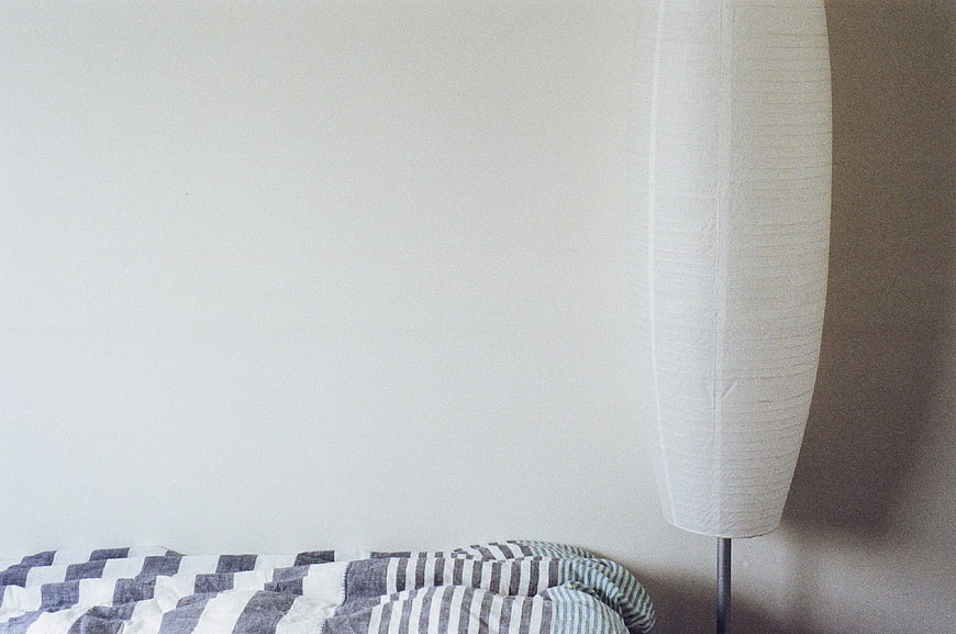 Minimalist Bedroom Corner with Striped Blanket and Floor Lamp