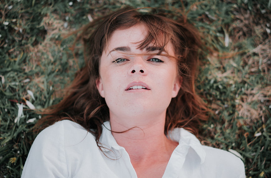 Woman lying in grass looking up at camera
