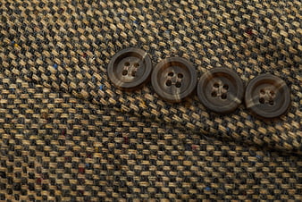 Close-up of brown buttons on textured tweed fabric