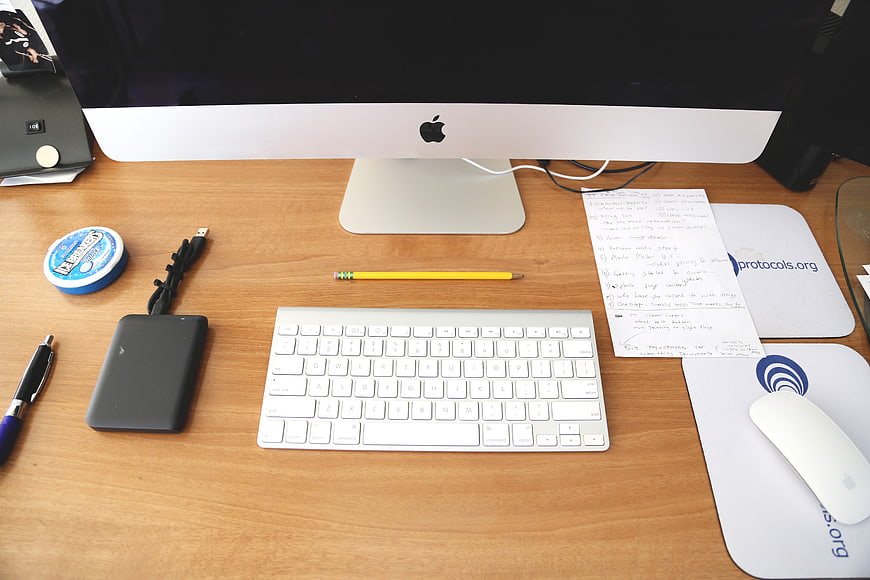 Organized wooden desk with iMac, keyboard, and office supplies