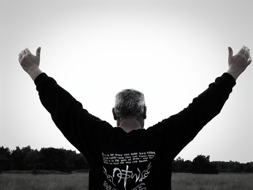 Man with arms raised in worship in black and white