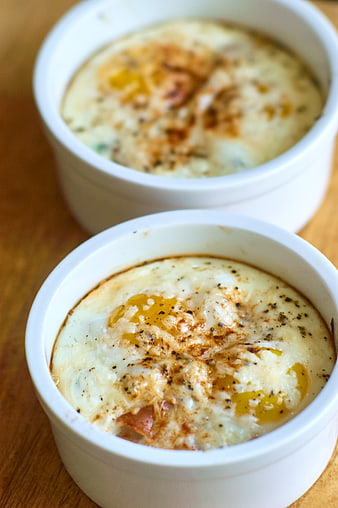 Close-up of baked eggs in white ramekins on wooden table