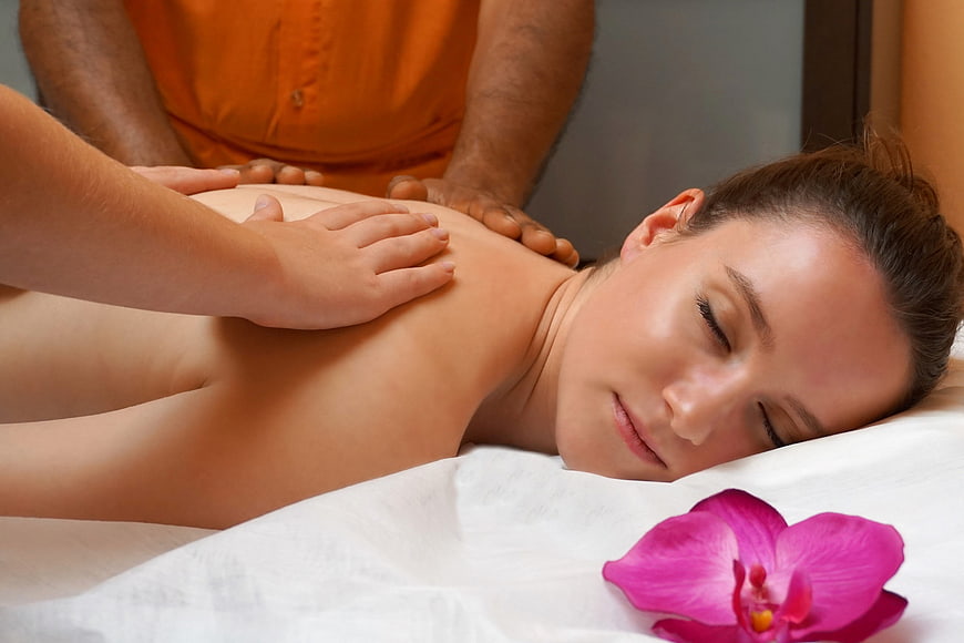 Woman Receiving Four-Hand Spa Massage With Orchid