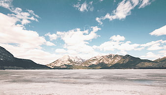 Frozen Lake with Snow-Capped Mountains and Blue Sky