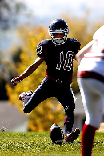 American Football Player Kicking Punt on Grass Field