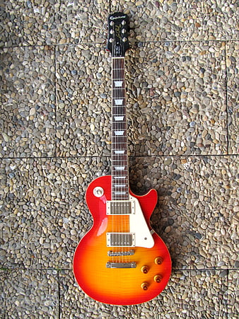 Red Epiphone Les Paul Electric Guitar On Pebble Paving