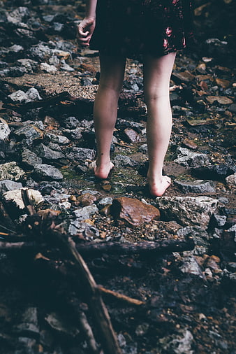 Barefoot woman walking on rocky stream bed