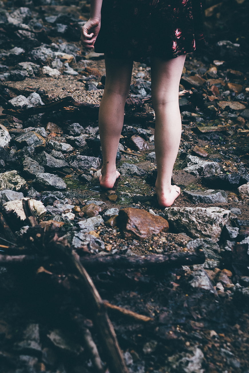 Barefoot woman walking on rocky stream bed