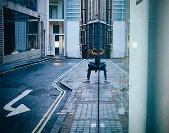Man sitting on wet city street looking at smartphone