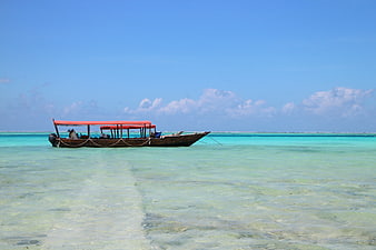 Traditional wooden boat with red canopy in turquoise tropical waters