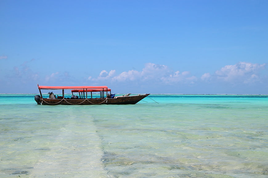 Traditional wooden boat with red canopy in turquoise tropical waters