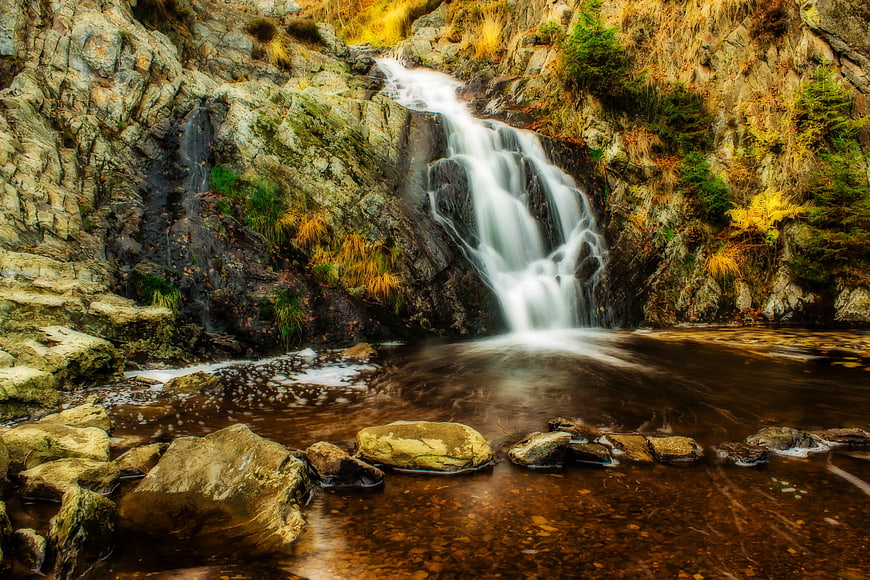 Serene waterfall cascading into a rocky stream pool