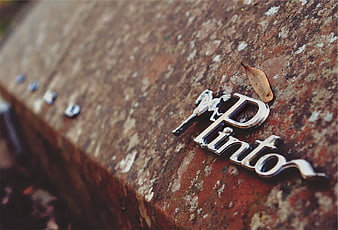 Rusty Ford Pinto Emblem Close-Up on Vintage Car