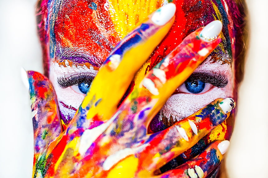 Colorful face paint portrait with hands covering eyes