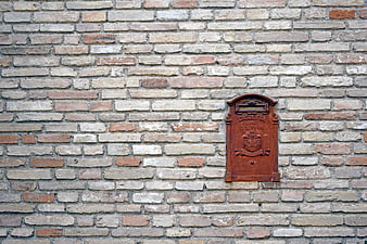 Rusty vintage mailbox mounted on textured brick wall