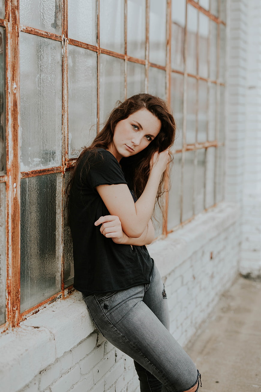 Young woman leaning against rustic industrial window wall