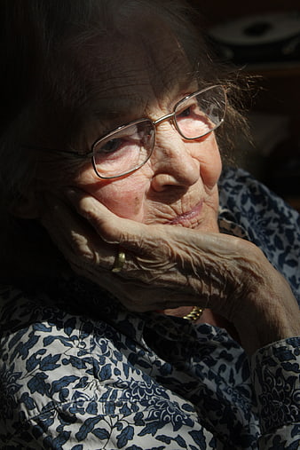 Contemplative Portrait of Elderly Woman with Glasses and Weathered Hands